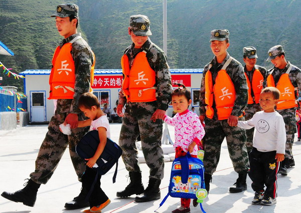 Soldiers and kids walk hand in hand to the makeshift classrooms of a newly-built kindergarten for victims of mudslide-hit Zhouqu in Gansu province on September 14, 2010. [Photo/Xinhua]