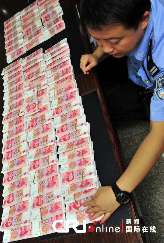 A police officer shows counterfeit Chinese currency renminbi seized during a recent operation in Xi’an, North China's Shaanxi province, Sept 14, 2010. The notes carried a value of 820,000 yuan ($121,571), the largest seizure in a decade in the province. The counterfeit money mainly circulated in entertainment centers and vegetable markets. 