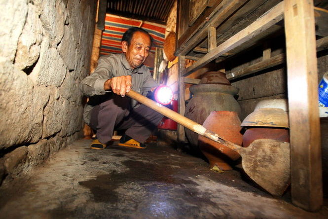 A villager searches for cobras in his house in Xianling village of Shijiao town in Chongqing, Sept 14, 2010. [sohu.com]