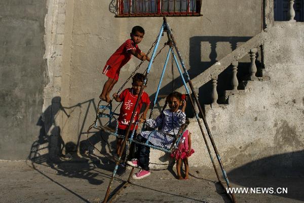 Palestinian children play the seesaw in front of their home in Deir al-Balah refugee camp, central Gaza Strip, on Sept. 15, 2010. [Xinhua]