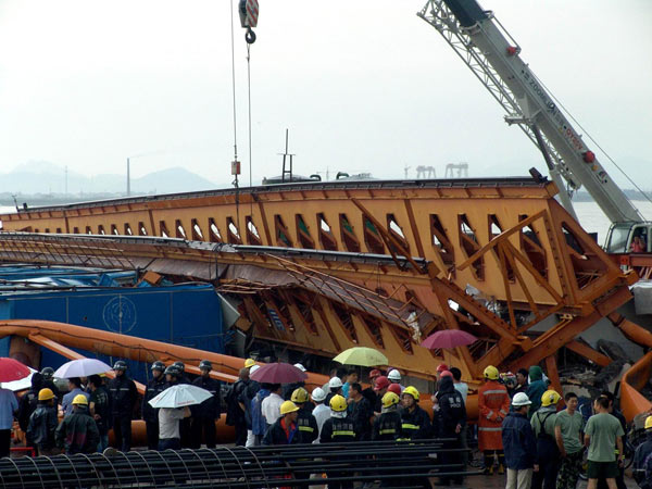 People crowd around the scene where a tower crane for constructing a bridge collapsed onto a work shed and buried 11 workers about 2 pm in Taizhou, East China&apos;s Zhejiang province, Sept 15, 2010. All the buried were pulled out alive but suffered some injuries. [Xinhua]