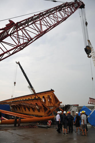 Rescue workers lift a tower crane, which collapsed onto a work shed and buried 11 workers in Taizhou, East China&apos;s Zhejiang province, Sept 15, 2010. [Xinhua]