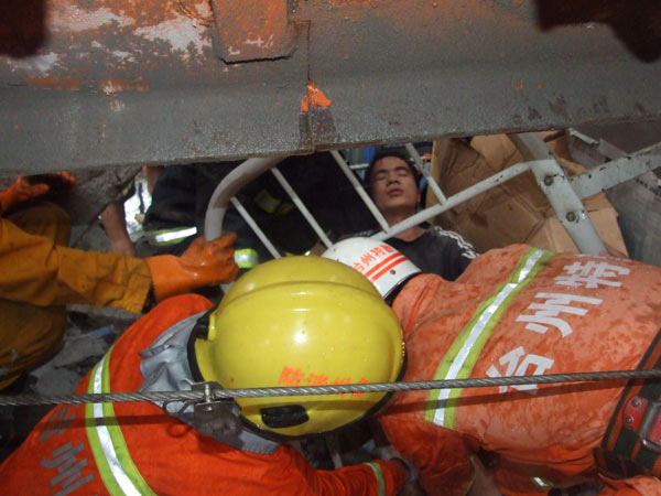 Rescuers pull out a man buried in the rubble after a tower crane collapsed onto a work shed and buried 11 workers in Taizhou, East China&apos;s Zhejiang province, Sept 15, 2010. [Xinhua]