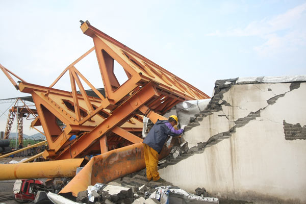 A worker checks for damages after a tower crane collapsed onto a work shed and buried 11 workers in Taizhou, East China&apos;s Zhejiang province, Sept 15, 2010. [Xinhua]