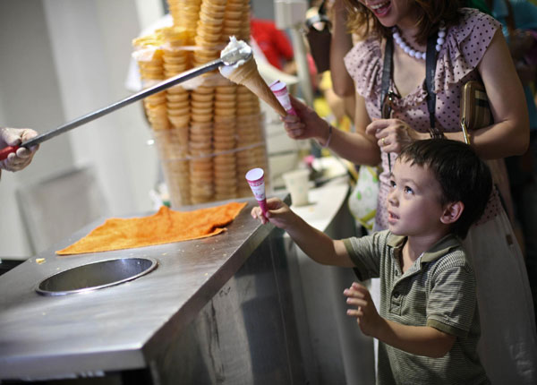 A boy waits for his ice cream at the Turkey Pavilion on Thursday. A staff member at the pavilion makes typical Turkish ice cream and teases some customer by pulling the scoop back just before giving them the ice cream. The customers laugh. [Xinhua] 