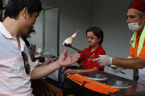 An ice cream cone flies away as a customer tries to grab it on Thursday. The staff at the Turkey Pavilion at the Shanghai Expo played tricks with their customers. [Xinhua] 