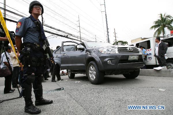 A policeman stands guard beside a vehicle after two policemen were killed in Quezon City, the Philippines, Sept. 16, 2010. [Xinhua]