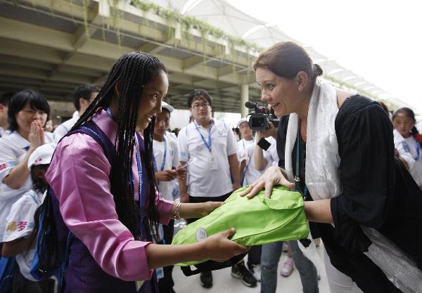 Doje Zhoima (L) from quake-hit Yushu County of northwest China's Qinghai Province receives a gift presented by an official of the Finland Pavilion at the World Expo Park in Shanghai, east China, Sept. 15, 2010. A total of 30 students of two hope schools in quake-hit Yushu County were invited by Unilever Co. to visit the 2010 World Expo on Wednesday.