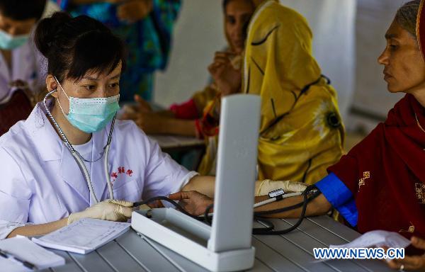 Li Jun, a doctor from China&apos;s Armed Police General Hospital, also a member of the second Chinese rescue team, measures the blood pressure for a patient at Makly town in flood-hit Thatta in southern Pakistan, Sept. 17, 2010. [Zhou Lei/Xinhua]