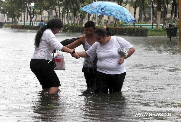 People walk on a flooded street in Veracruz, Mexico, Sept. 17, 2010. Hurricane Karl on Friday struck Mexico&apos;s east coast, killing two people and forcing the country to shut down the Laguna Verde nuclear power station, a local radio reported. [Jorge Dan/Xinhua]