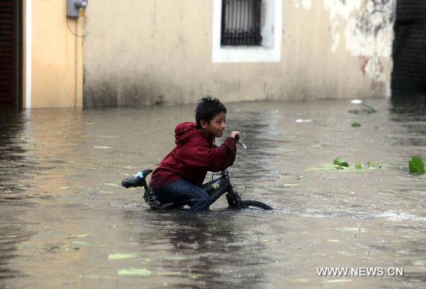 A boy rides a bike on a flooded street in Veracruz, Mexico, Sept. 17, 2010. Hurricane Karl on Friday struck Mexico&apos;s east coast, killing two people and forcing the country to shut down the Laguna Verde nuclear power station, a local radio reported. [Jorge Dan/Xinhua]