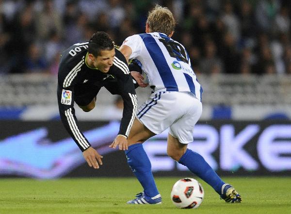 Real Madrid's Cristiano Ronaldo (L) and Real Sociedad's Diego Rivas Gutierrez fight for the ball during their Spanish First Division soccer match at the Anoeta stadium in San Sebastian September 18, 2010. Real Madrid beats Real Sociedad 2-1.(Xinhua/Reuters Photo)