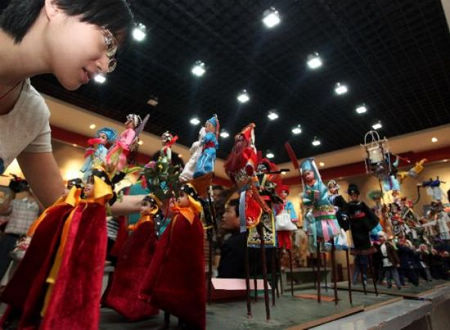 A visitor appreciates sculptures of 'shehuo', an ancient form of gala, during a farmer cultural festival held at the mass art center in Xi'an, capital of northwest China's Shaanxi Province, Sept. 15, 2010. Fifty-four folk artists displayed their stunts on the farmer cultural festival on Wednesday. Photo: Xinhua 