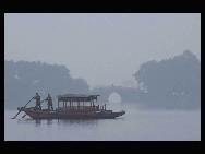 File photo taken in Jan. 2006 shows two people rowing a boat on the West Lake in Hangzhou, capital of east China's Zhejiang Province.  [Xinhua/Tan Jin]