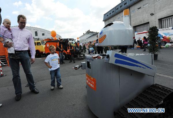A father and two kids look at a litter pick-up robot at garbage festival held by MA48, or Vienna urban waste disposal center, in Vienna, capital of Austria, Sept. 19, 2010. The two-day festival aims at demonstrating waste classification and popularizing environmental protection conception. [Xinhua]