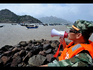 An armed policeman shouts to urge fishermen to land in Lianjiang County, southeast China's Fujian Province, Sept. 19, 2010. [Xinhua]