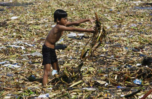 A volunteer tosses waste material as he participates in a coastal clean-up drive in Manila Bay, Sept 19, 2010. Dozens of volunteers joined in the International Coastal Clean-up drive to remove debris and rubbish from shorelines, waterways and oceans for a cleaner marine environment. [China Daily/Agencies]