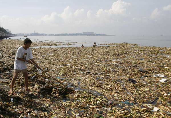 A volunteer collects waste material floating on the water during a coastal clean-up drive in Manila Bay, Sept 19, 2010. [China Daily/Agencies]