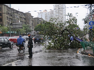A policeman stands beside a tree branch fallen on the ground in Xiamen of southeast China's Fujian Province, Sept. 20, 2010. Typhoon Fanapi, the 11th and strongest typhoon to hit China this year, hit Gulei Township in Fujian's Zhangpu County, lashing the province's coastal areas with winds and torrential rains. [Xinhua]