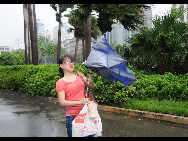 A woman holds her umbrella turned inside out in strong winds in Xiamen of southeast China's Fujian Province, Sept. 20, 2010. [Xinhua]