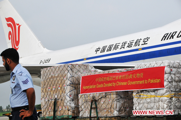 A guard stands beside humanitarian goods donated by the Chinese government at a military airport in Rawalpindi, Pakistan, Aug. 19, 2010. [Yan Zhonghua/Xinhua]