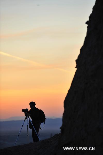 A tourist takes pictures at Urho Wind City over 100km northeast of Kramay City, northwest China's Xinjiang Uyghur Autonomous Region on Sept. 19, 2010. Urho Wind City, with its unique wind-eroded geological feature, is one of the attractive scenic spots in Xinjiang. [Xinhua/Lu Peng]