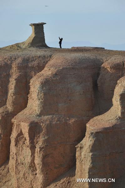 A tourist takes pictures at Urho Wind City over 100km northeast of Kramay City, northwest China's Xinjiang Uyghur Autonomous Region on Sept. 19, 2010. Urho Wind City, with its unique wind-eroded geological feature, is one of the attractive scenic spots in Xinjiang. (Xinhua/Lu Peng) 