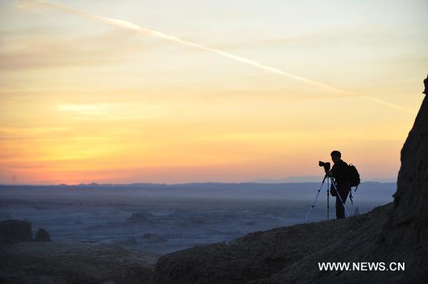 A tourist takes pictures at Urho Wind City over 100km northeast of Kramay City, northwest China's Xinjiang Uyghur Autonomous Region on Sept. 19, 2010. Urho Wind City, with its unique wind-eroded geological feature, is one of the attractive scenic spots in Xinjiang. [Xinhua/Lu Peng]