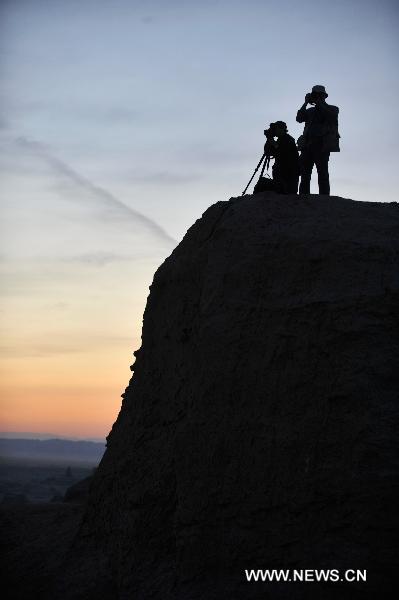 Tourists take pictures at Urho Wind City over 100km northeast of Kramay City, northwest China's Xinjiang Uyghur Autonomous Region on Sept. 19, 2010. Urho Wind City, with its unique wind-eroded geological feature, is one of the attractive scenic spots in Xinjiang. [Xinhua/Lu Peng]