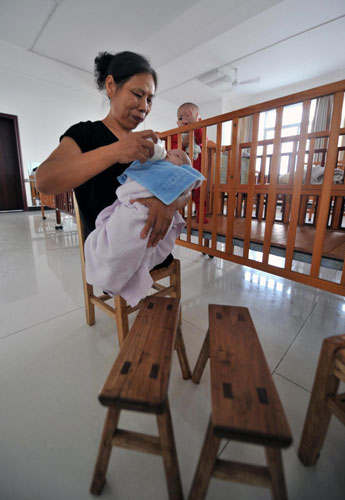 Xu feeds a baby orphan at Xiangtan Social Welfare House in Xiangtan, Central China&apos;s Hunan province, Sept 15, 2010. [Xinhua] 
