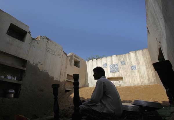 A man, displaced by flooding, sits in his roofless house at his flooded village in Dadu, some 320 km (198 miles) north of Karachi, Sept 20, 2010. [China Daily/Agencies]