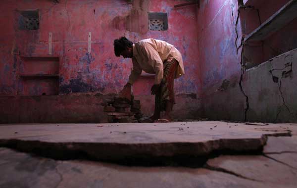 Mujtaba, 30, displaced by flooding, collects bricks from the damaged floor of his house after returning to his flooded village in Dadu. [China Daily/Agencies]