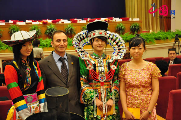A foreign representative poses for photo with girls of Chinese ethnic groups. [Maav Chen / China.org.cn]