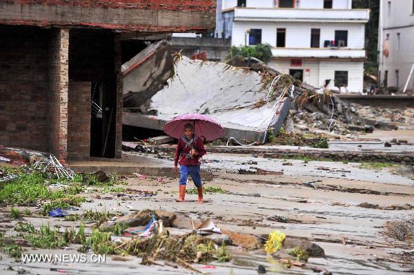 An elderly carrying a baby on the back walks in Qianpai Town in Xinyi, south China's Guangdong Province, Sept. 22, 2010. Flooding and landslides caused by Typhoon Fanabi have left 18 people dead and at least 44 still missing, according to the Ministry of Civil Affairs on Wednesday. [Chen Yehua/Xinhua]