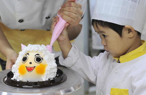 A student is helped by an instructor as she decorates a cake during a cooking class at a youth recreation centre in Shenyang, Northeast China&apos;s Liaoning province on Friday. [China Daily/Agencies] 