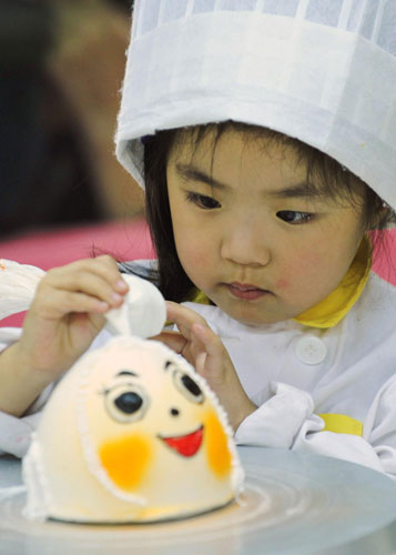 A girl decorates a cake during a cooking class at a youth recreation centre in Shenyang, Liaoning province on Friday. [China Daily/Agencies] 