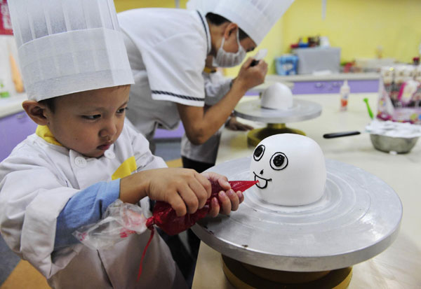 A boy decorates a cake during a cooking class at a youth recreation centre in Shenyang, Liaoning province on Friday.[China Daily/Agencies] 