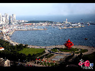 May Fourth Square, symbol of Qingdao, is a large public square located between the new municipal government building and Fushan Bay and composed of Shizhengting Square, the central square and the coastal park. Named after the nationwide protest May Fourth Movement that started in Qingdao, the square is best recognized by the large 'May Wind' red sculpture near the seaside. [Cheng Weidong/China.org.cn]