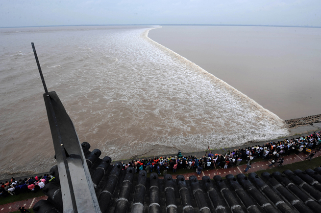 Visitors look at the surging tide of the Qiantang River in Haining, East China&apos;s Zhejiang province, Sept. 25, 2010. [Xinhua]