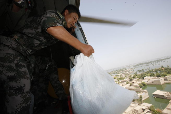 A member of the Chinese helicopter rescue team delivers relief materials when the helicopter flies above a flooded area 160 km away from Hyderabad, Pakistan, Sept. 25, 2010. The Chinese helicopter rescue team accomplished its first mission in flooded areas in Pakistan on Saturday. [Xinhua]