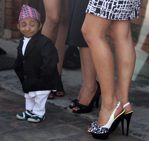 Khagendra Thapa, who is expected to be the world&apos;s shortest man next month when he turns 18, looks at the legs of Miss Nepal beauty pageant winners during a news conference in Kathmandu, capital of Nepal, Sept 24, 2010. The Nepal Tourism Board has nominated Thapa and Miss Nepal beauty pageant winners as goodwill ambassadors to promote tourism in Nepal. Thapa will carry the message: &apos;Shortest man in the world from the highest mountain in the world invites you to visit Nepal. [China Daily/Agencies]