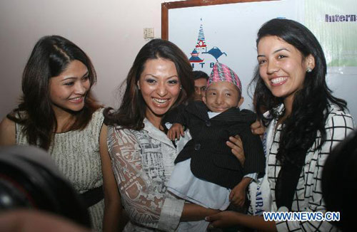 Khagendra Thapa is carried by Miss Nepal 2010 Sadichha Shrestha (R) and first runner-up Sahana Bajracharya (C) as second runner-up Sanyukta Timsina (L) smiles during a news conference in Kathmandu, Nepal, Sept 24, 2010. [Xinhua]