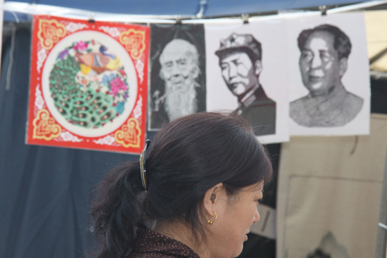 A visitor is pictured in front of paper-cut works, including two portraits of former Chinese leader Mao Zedong, at the 9th Book Fair held in the Ditan Park, Beijing, Sept 24, 2010. [chinadaily.com.cn]