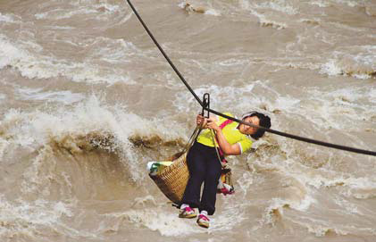 A villager ferries supplies along a zip wire across the Nujiang River. 