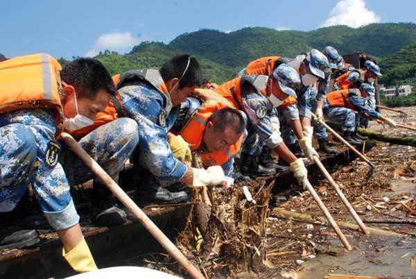 Soldiers clean up floating debris along the upper reaches of a river on Sunday in Gaozhou, Guangdong, to safeguard a local reservoir from possible threat. Floods and mudslides triggered by Typhoon Fanapi caused heavy death tolls in the province. [Xinhua]