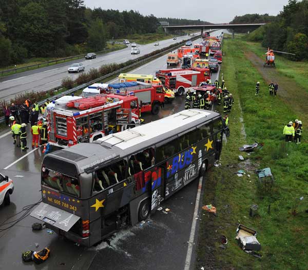 Emergency services stand next to the wreckage of a bus and a car following an accident on the A10 motorway near Schoenfeld south of Berlin September 26, 2010. [Xinhua/AFP]