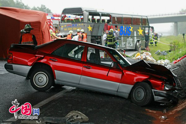 Firemen and rescue workers stand around a tour bus that crashed into a concrete bridge support on the A10 highway on September 26, 2010 near Berlin, Germany. According to police on site at least 11 people were killed and 7 seriously injured. According to medai reports the bus was carrying Polish youth home from a trip to Spain and the bus crashed after attempting to pass a merging car. [CFP]