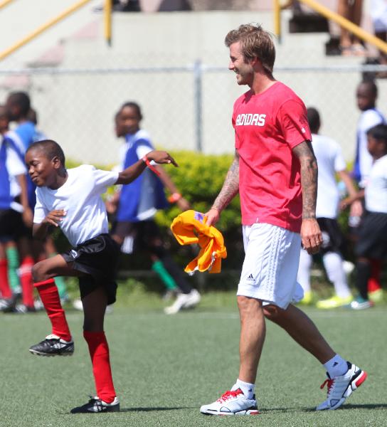 A boy plays with David Beckham at the launch of the David Beckham Academy at Marvin Lee Stadium in Macoya September 26, 2010. The Academy will provide football and life skills programmes as well as coaching workshops to almost 200 young players and coaches. The commitment was made at the FIFA World Cup 2010 Final Draw in Cape Town last December. (Xinhua/Reuters Photo)