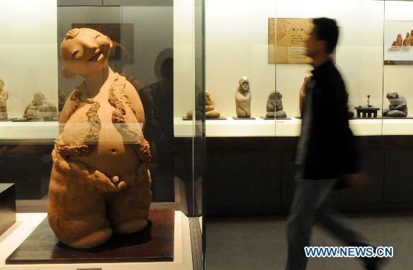 A visitor passes by a piece of mud sculpture at Hebei Folklore Museum in Shijiazhuang, capital of north China's Hebei Province, Sept. 26, 2010. The folklore museum started recently an exhibition of mud sculptures featuring country lives.