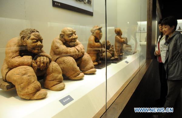 Visitors look at mud sculptures at Hebei Folklore Museum in Shijiazhuang, capital of north China's Hebei Province, Sept. 26, 2010. The folklore museum started recently an exhibition of mud sculptures featuring country lives.